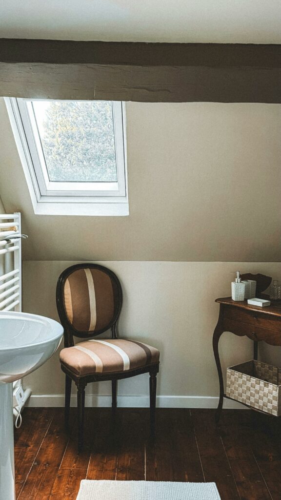 Elegant bathroom with a skylight window, vintage chair, and classic decor.